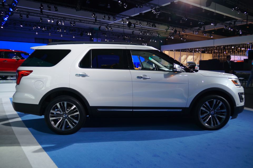 White SUV parked on a blue carpeted floor at an indoor event.