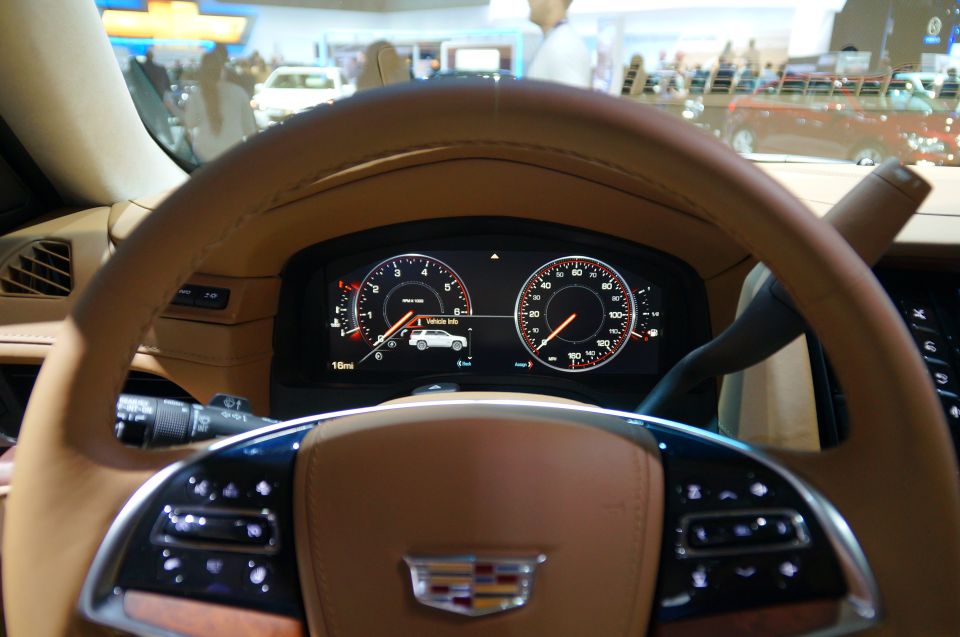 Close-up of a car's digital dashboard and steering wheel.