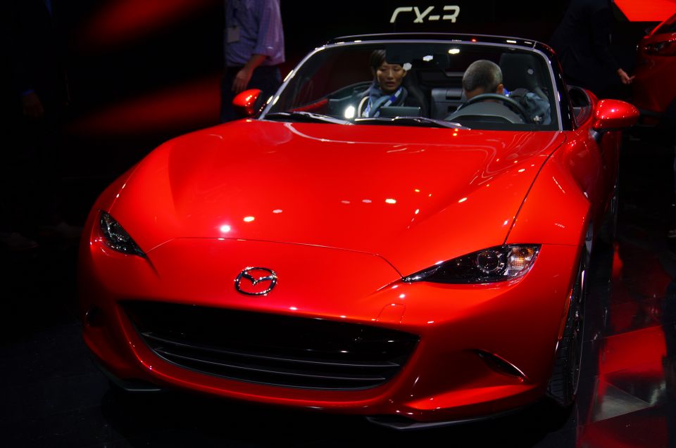 Red Mazda convertible with sharp headlights and Mazda logo on the grille.
