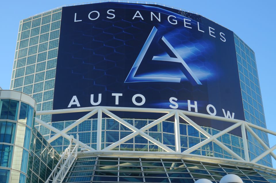 Los Angeles Auto Show banner on a modern building with glass facade and white support structure.