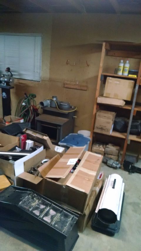 Cluttered garage with boxes, stove, shelves, and a black ramp.