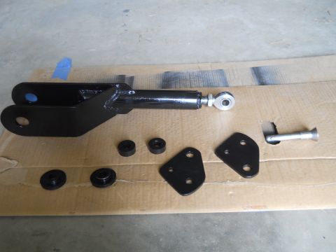 1992 Ford Bronco - Black painted suspension components, including a U-shaped bracket with a rod end, are laid out on a piece of cardboard.