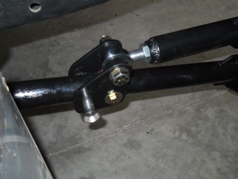 1992 Ford Bronco - Close-up of a black adjustable sway bar end link connected to a black sway bar, mounted on a concrete floor.