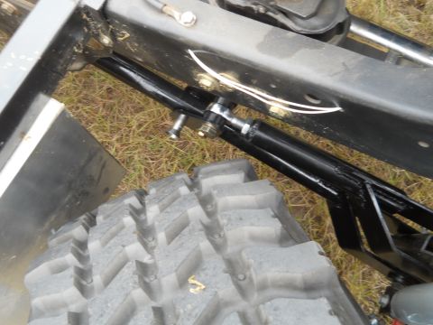 1992 Ford Bronco - A close-up view of the suspension and tire of a vehicle, showing a black hydraulic cylinder attached to the frame and a large, aggressive t…