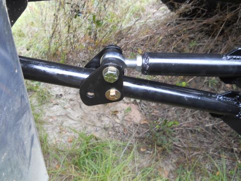 1992 Ford Bronco - A close-up view shows a black metal suspension component, likely part of a steering or linkage system, attached to a black bar with two bol…