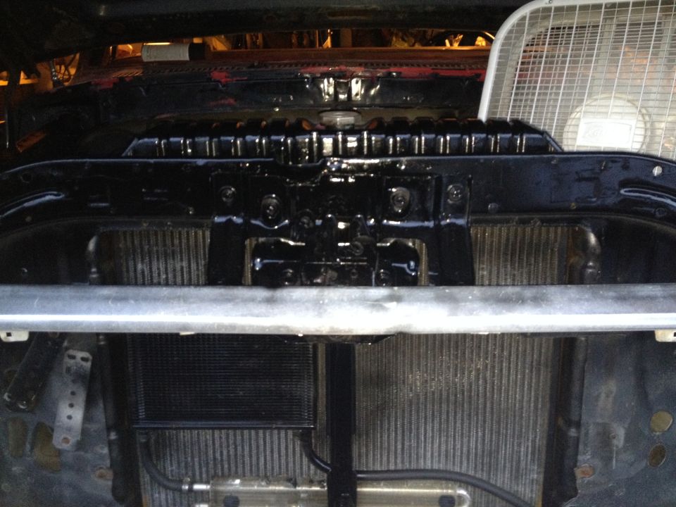 Close-up of vehicle radiator and oil cooler assembly with a fan in the background