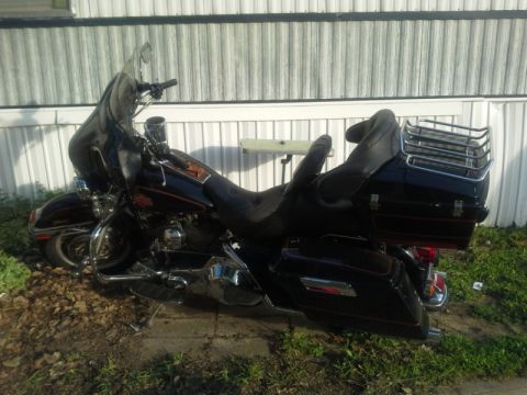 1993 Ford Bronco - A black Harley-Davidson Electra Glide motorcycle is parked on the grass in front of a building.