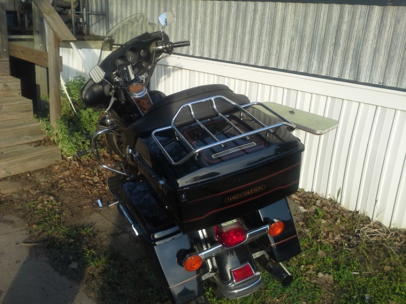 Harley-Davidson motorcycle rear view with saddlebags and luggage rack. Text 'HARLEY-DAVIDSON' visible on saddlebag
