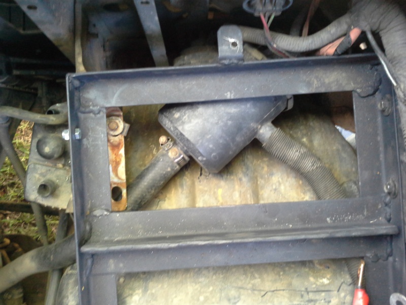 Black welded steel frame around a fuel tank with filler neck hoses and wiring on a 1993 Ford Bronco