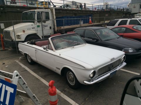 1968 Ford Mustang - A white convertible car is parked in a lot next to other vehicles.