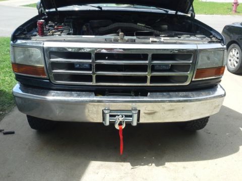 1993 Ford Bronco - A winch is installed on the front bumper of a Ford truck, with the hood open revealing the engine bay.