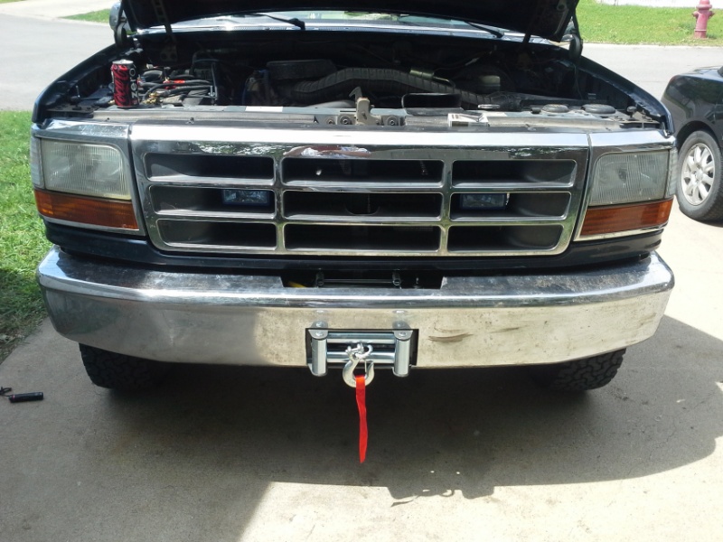 Front view of a dark-colored Ford truck with a chrome grille and a winch mounted on the bumper