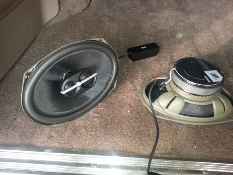 1994 Ford Bronco - Two car speakers, an oval and a round JBL, are shown on a carpeted vehicle floor.