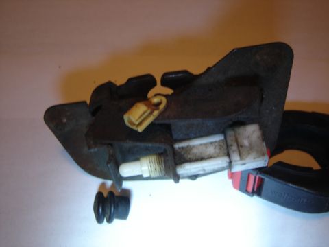 1996 Ford Bronco - A removed tailgate latch assembly sits on a light workbench, gripped in a black Wolfcraft clamp: rusty stamped-steel bracket with a white p…