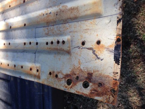 1979 Ford Bronco - A heavily rusted metal panel with multiple holes and blue markings is shown.