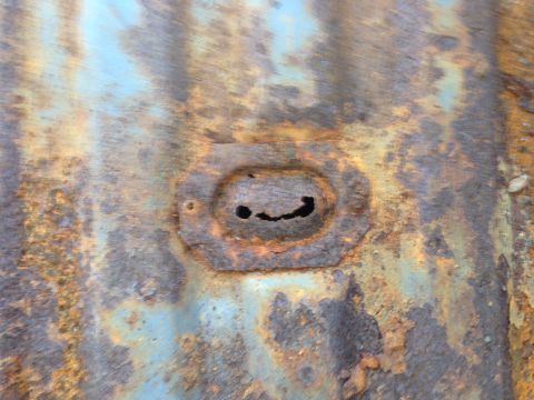 1979 Ford Bronco - This heavily rusted metal panel features an oval cutout that gives the appearance of a face.
