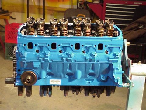1989 Ford Bronco - A blue V8 engine block is shown with its internal components partially exposed, resting on a stand.