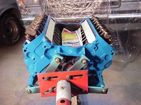 1989 Ford Bronco - A blue engine block is mounted on a stand, with a newspaper tucked inside its cylinders.