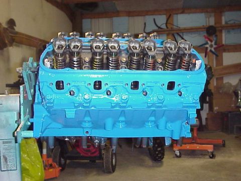 1989 Ford Bronco - A bright blue V8 engine is shown on an engine stand, with its valve train components visible.