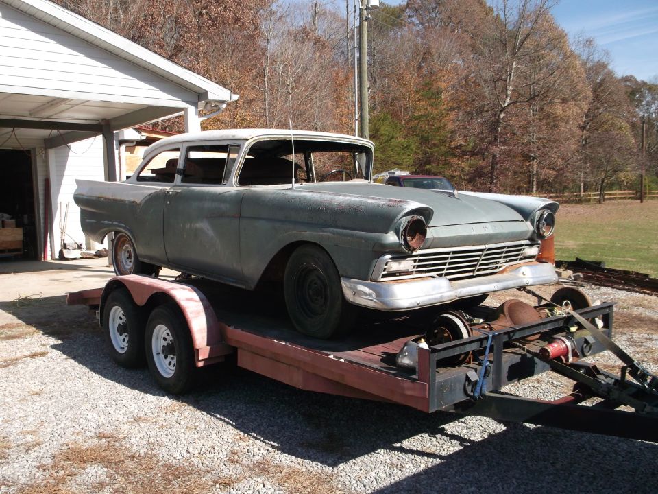Gray 1957 Ford Custom Sedan on a trailer, front 3/4 view, missing headlights and grille