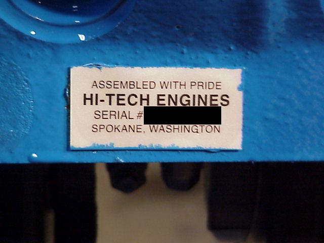 Blue engine block with a label reading 'ASSEMBLED WITH PRIDE HI-TECH ENGINES SERIAL # SPOKANE, WASHINGTON'