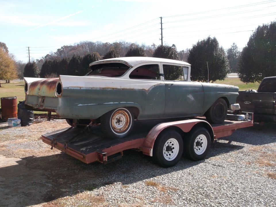 1957 Ford Custom Sedan on a trailer, two-tone green and white, showing rust on the rear fins