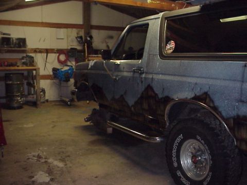 1989 Ford Bronco - This 1989 Ford Bronco is seen in a garage with custom mountain-themed paint and aftermarket running boards.