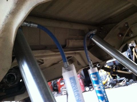 1995 Ford Bronco - Close-up of vehicle undercarriage components, including shock absorbers and hydraulic lines.