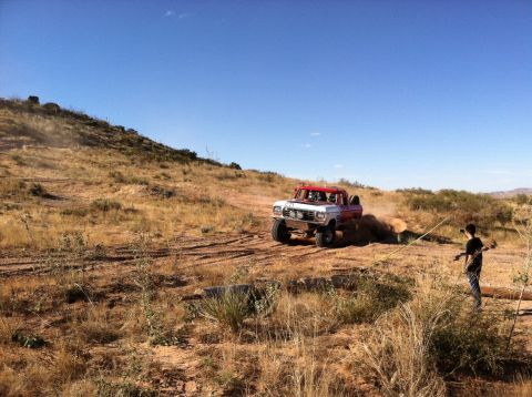 1995 Ford Bronco - Off-road truck navigates a dry, dusty landscape under a clear blue sky.