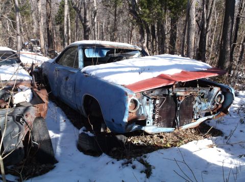 1974 Dodge Challenger - This weathered vehicle sits abandoned in a snowy, wooded area, its hood open and front end showing significant damage.