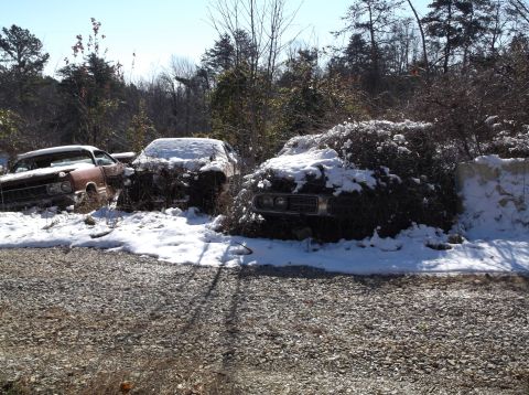 1974 Dodge Challenger - Several old cars, including a 1974 Dodge Challenger, sit in a snowy junkyard scene.
