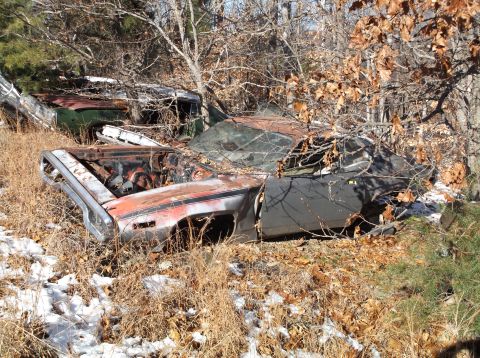 1974 Dodge Challenger - Two derelict vehicles sit abandoned in a wooded area, covered in leaves and snow.