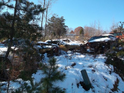 1974 Dodge Challenger - Multiple abandoned vehicles are covered in snow under a clear blue sky.