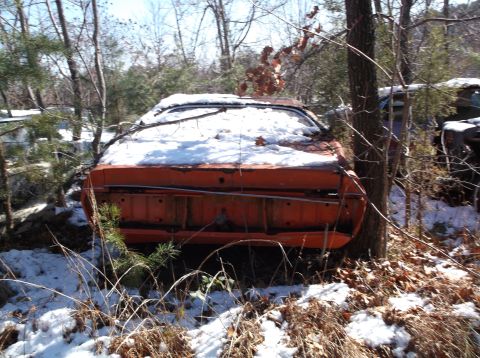 1974 Dodge Challenger - Rear view of an orange 1974 Dodge Challenger covered in snow, parked outdoors amongst trees.