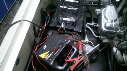 1982 Ford Bronco - Connecting a battery charger to the car battery. Brake fluid reservoir is also visible.