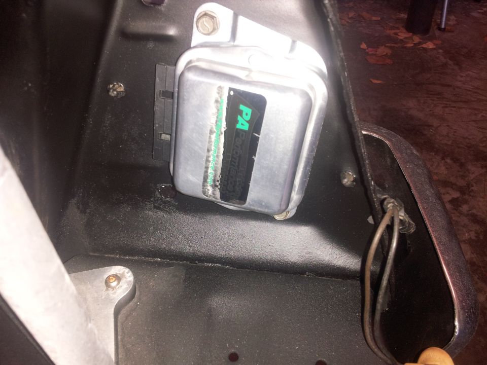 Rectangular silver electrical component with a green and black label, mounted on a black surface