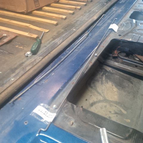 1978 Ford Bronco - Close-up of the interior floor of a vehicle, showing some tools and parts. The label on the plastic bag is partially visible.