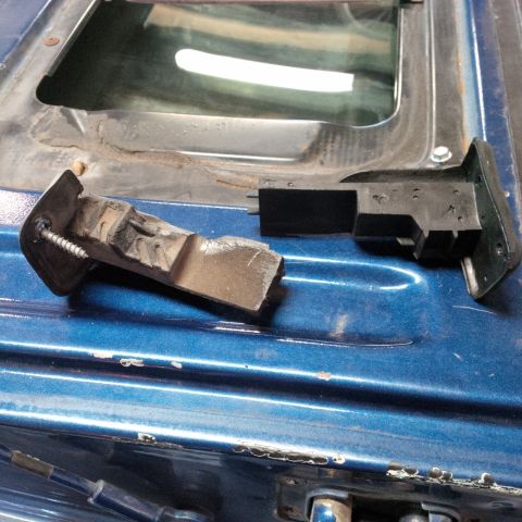 1978 Ford Bronco - Close-up of a broken latch mechanism on a blue vehicle's tailgate.