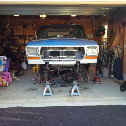 1978 Ford Bronco - Front end of a 1978 Ford Bronco undergoing maintenance in a garage.