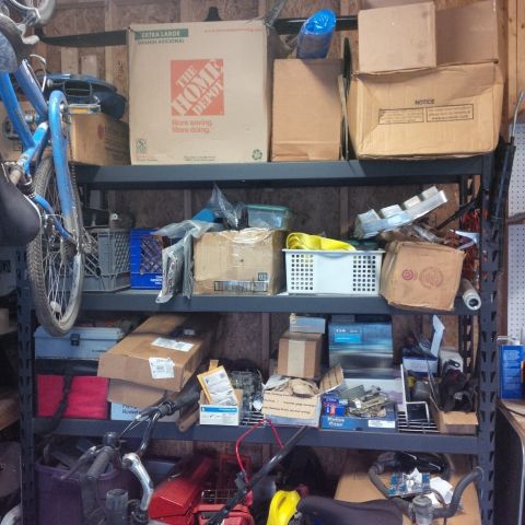 1978 Ford Bronco - A cluttered storage space filled with boxes, a bicycle, and miscellaneous items on metal shelving units.