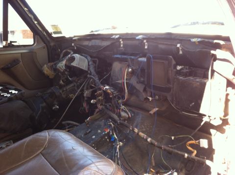 1995 Ford Bronco - The interior of a vehicle shows a disassembled dashboard with a complex network of exposed wiring and electrical components.