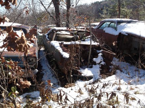 1974 Dodge Challenger - Abandoned 1974 Dodge Challenger sits in a snowy junkyard, its interior and engine bay exposed and rusted.