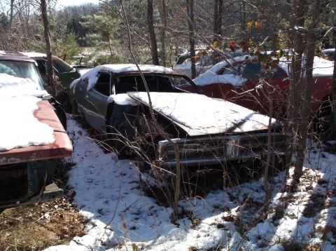 1974 Dodge Challenger - This car is in a junkyard and is covered in snow. Other vehicles are visible in the background.