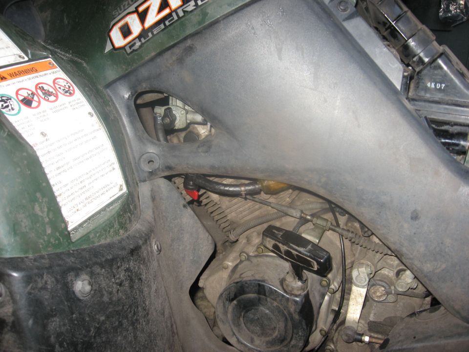 Green Suzuki QuadRunner engine with visible fuel line and carburetor