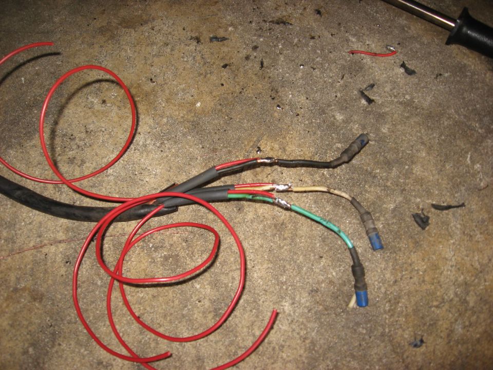 Electrical wires with solder and heat shrink tubing on a concrete surface.