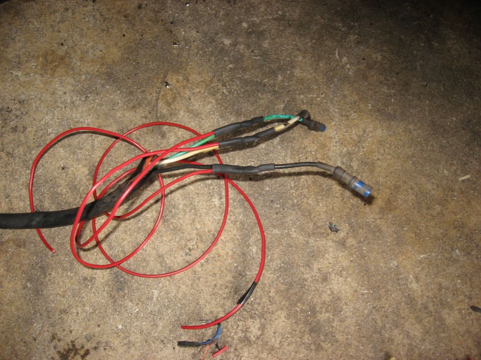 Bundle of wires with red, black, green, and white colors on a concrete surface.