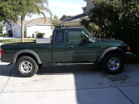 1985 Ford Bronco - A green Ford Ranger pickup truck is parked in a residential driveway on a sunny day.