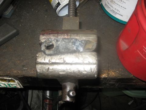 1994 Ford Bronco - This image shows a close-up of a metal vise holding two metal blocks. A red plastic container and a can are visible in the background.