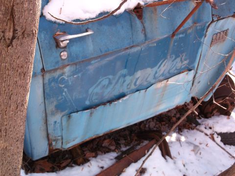 1974 Dodge Challenger - A close-up view of the side of a weathered, light blue vintage vehicle, possibly a truck or van, with a chrome door handle and visible rust…