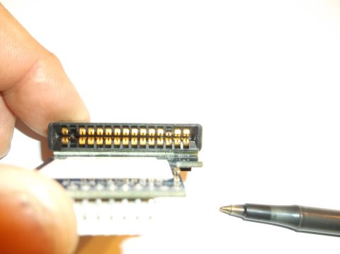 1979 Ford Ranchero - A person's fingers hold a small electronic connector with gold pins. A pen tip is visible in the lower right corner.